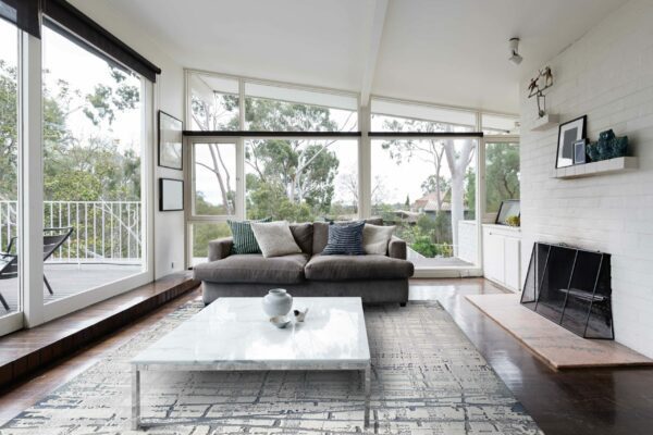 Mid century modern living room with huge windows to view the Australian treetops