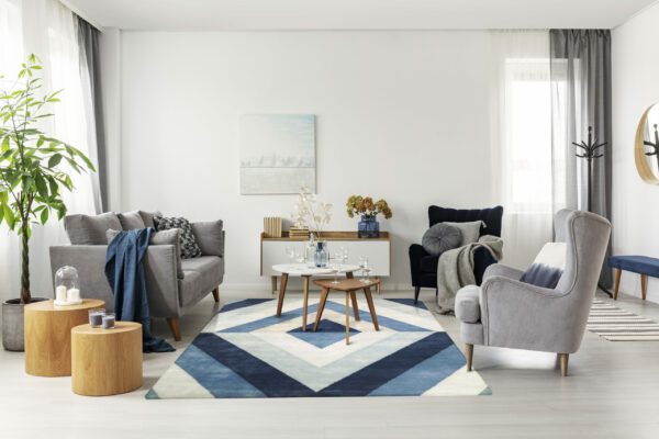 Grey and navy blue living room interior with comfortable sofa and armchairs