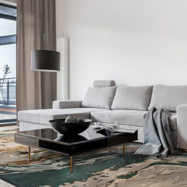 Stylish living room with simple, gray corner sofa and square, black coffee table
