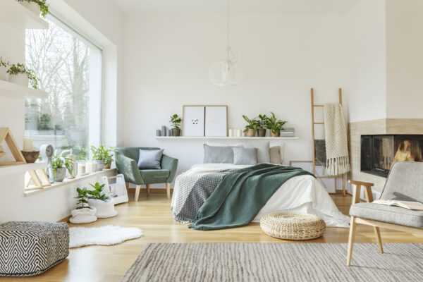 Spacious furnished bedroom interior with hed, fireplace, chair, armchair, rug and ornaments