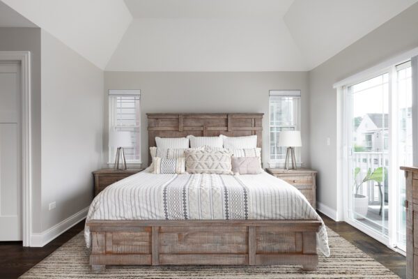 A beautiful bedroom with natural wood furniture, a glass door leading to a outdoor patio, and a cathedral ceiling.